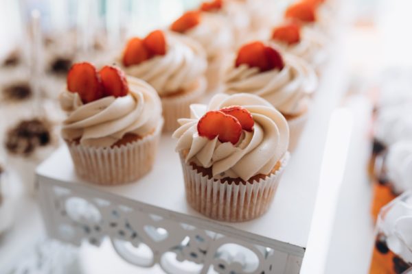 Tasty cupcake with creamy topping and slice of strawberry on the top, sweet buffet