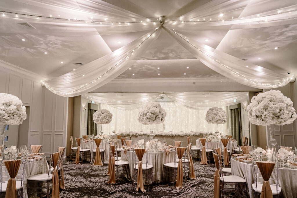 The ballroom at The Coniston Set up for a white a rose gold designed wedding, with round tables and a long top table.