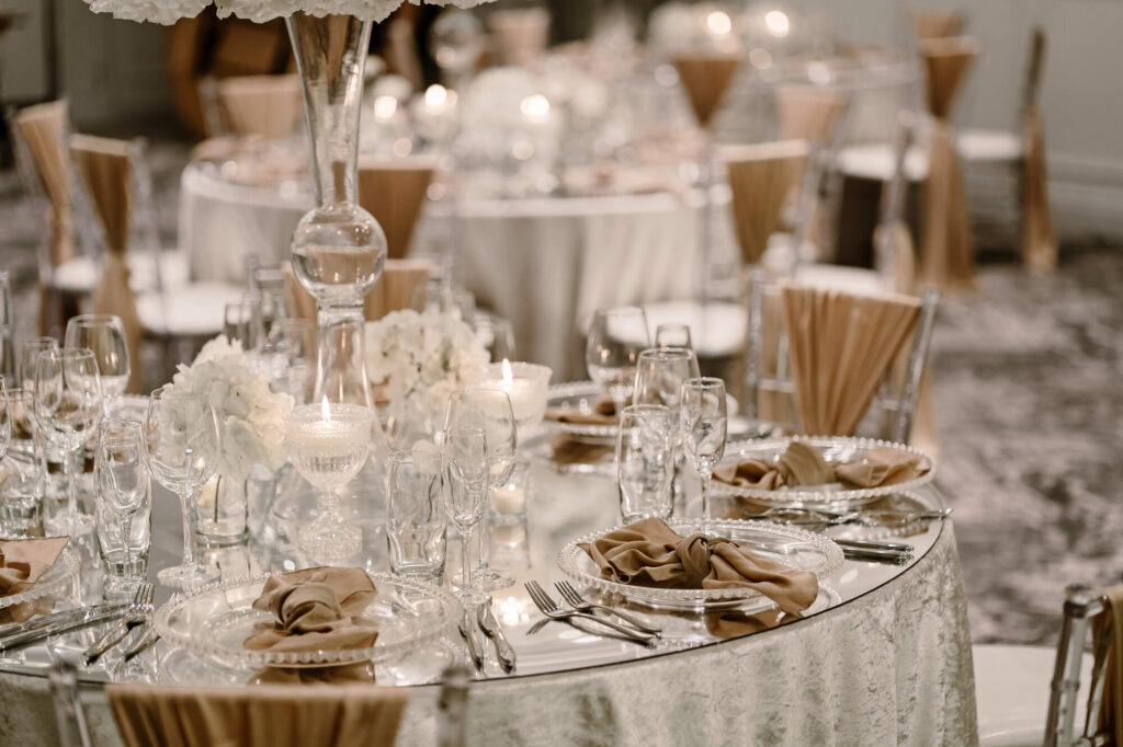 Table set up for a wedding with a mirrored table top, and use gold accompaniments